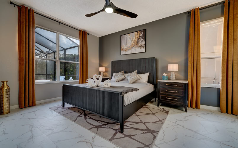 Sophisticated king bedroom with dark wood bed frame and ensuite spa bath at Marble Studios Florida in Kissimmee