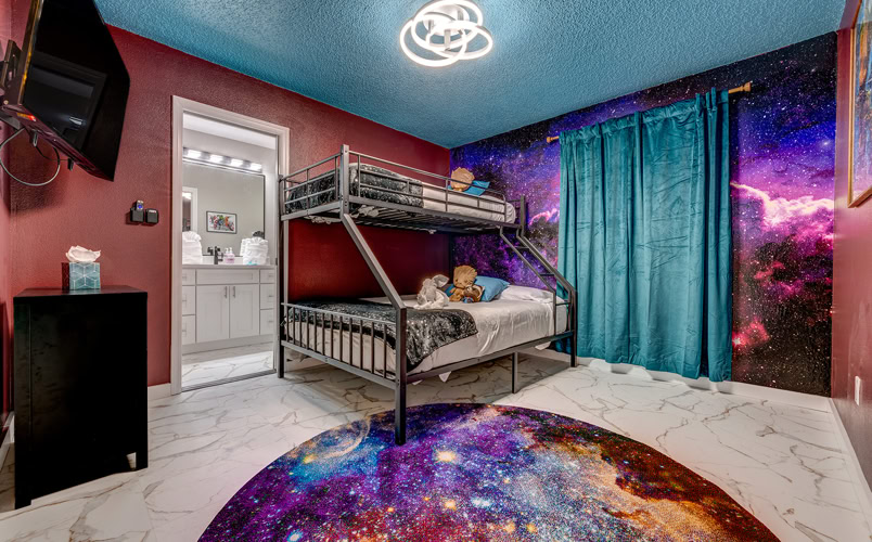 Vibrant space-themed kids bunk bedroom with starry wall mural and ensuite bathroom at Marble Studios Florida in Kissimmee