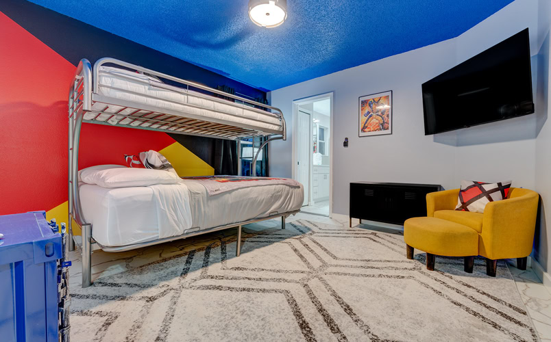 Colorful superhero-themed bunk bedroom with TV and private bath at Marble Studios Florida in Kissimmee