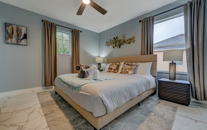 Spacious modern king bedroom with neutral decor and large windows at Marble Studios Florida in Kissimmee
